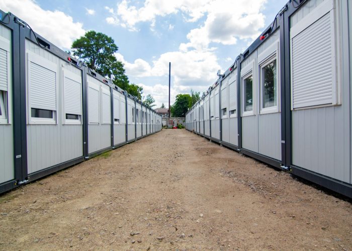 A clear sky view of two rows of temporary office buildings with a dirt pathway in between.